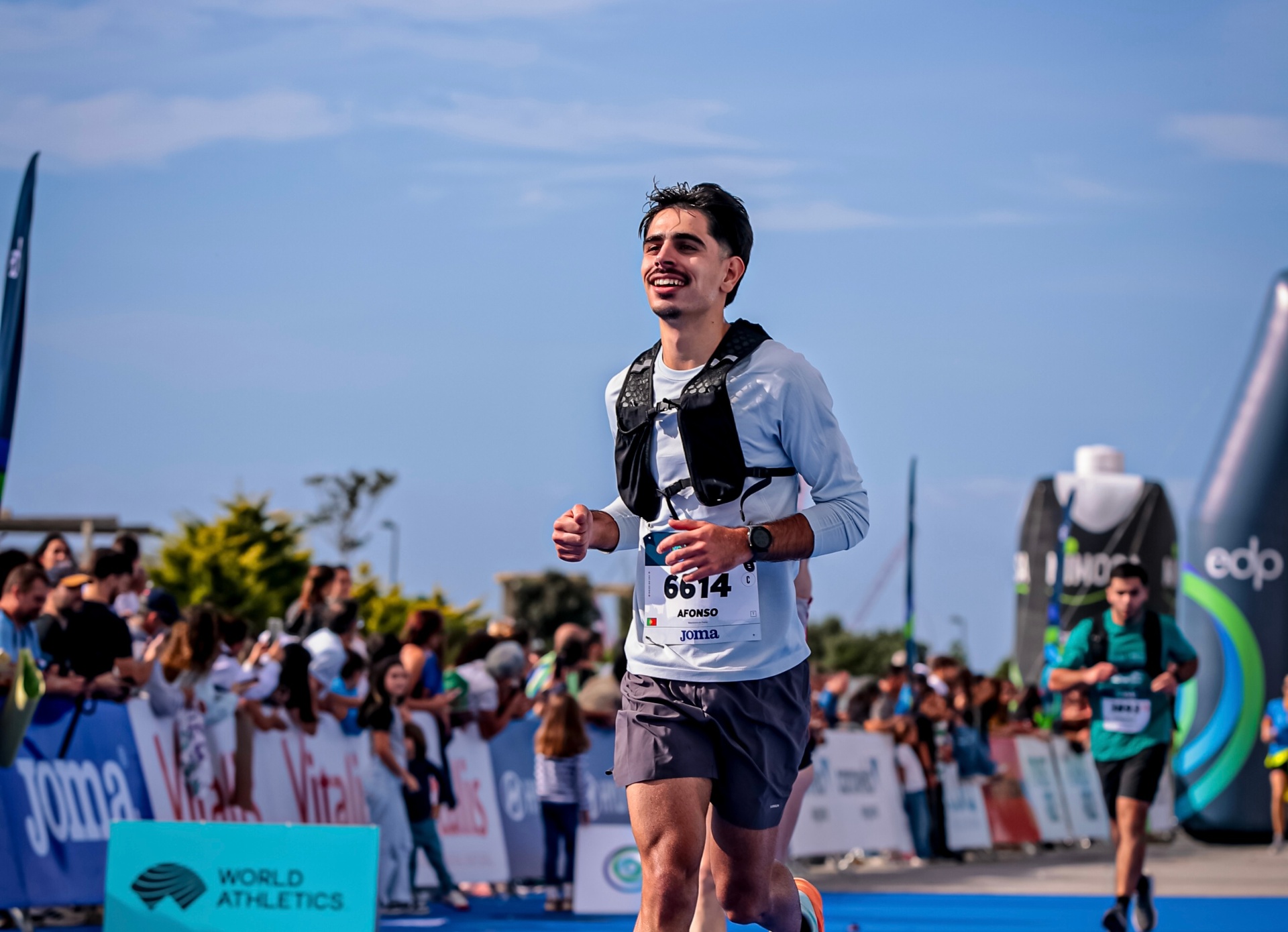Afonso a sorrir aparentemente a cruzar a linha de chegada da Maratona EDP, sobre o tapete azul