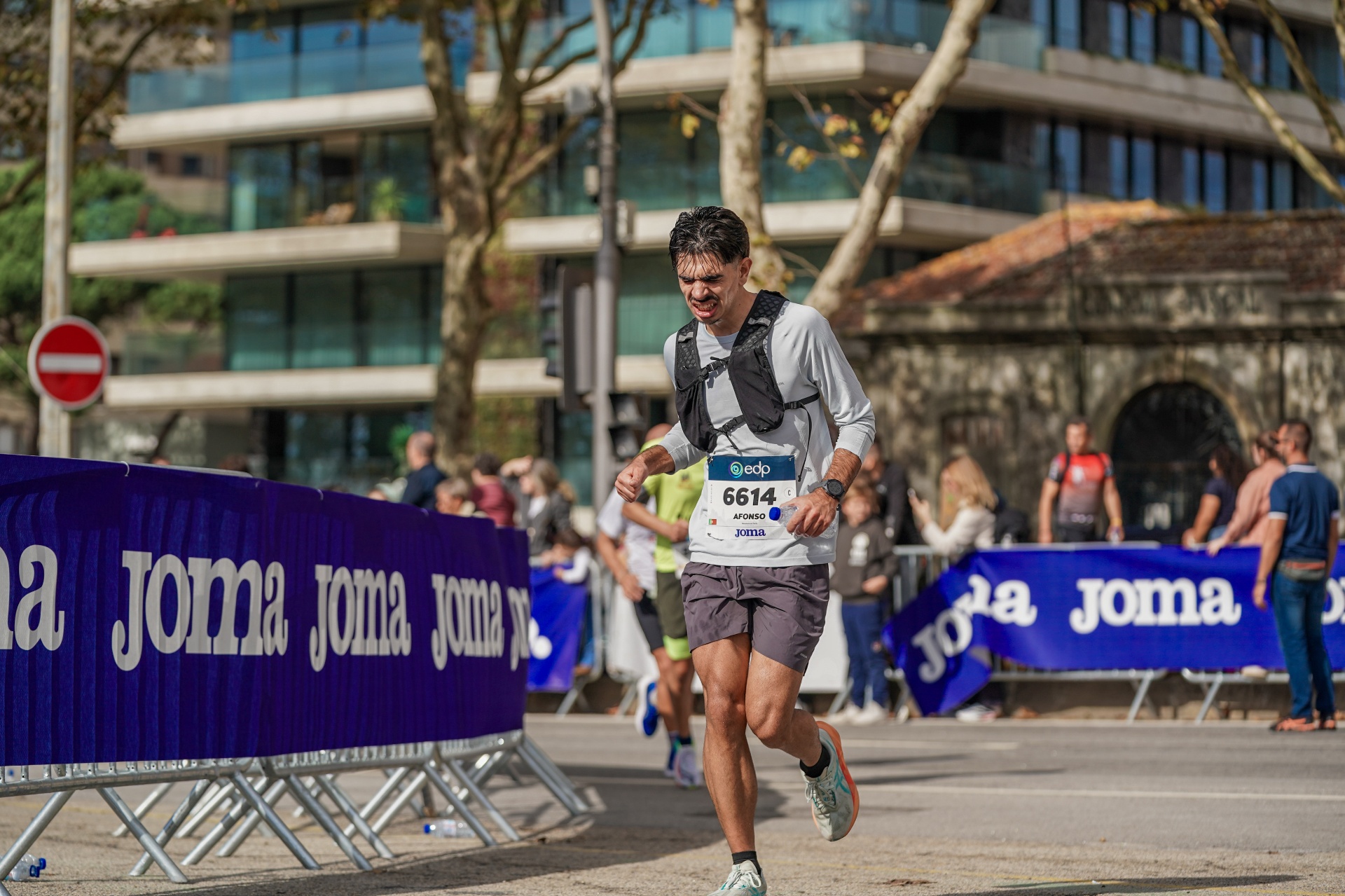 Afonso visivelmente em esforço a correr junto às barreiras da Joma, expressão de luta